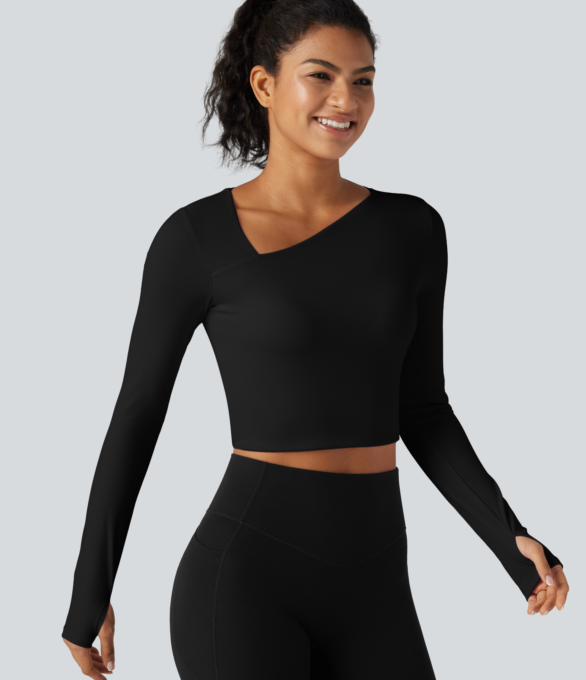 Verkürztes Yoga-Sport-Top mit asymmetrischem Ausschnitt, langen Ärmeln, Daumenlöchern und eingenähten Pads - Schwarz